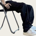 Person wearing black pants with white specks and white sneakers