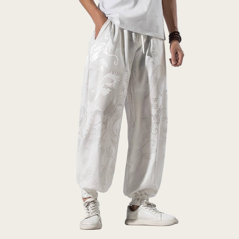 Person wearing white pants with floral patterns and white sneakers on a light yellow background