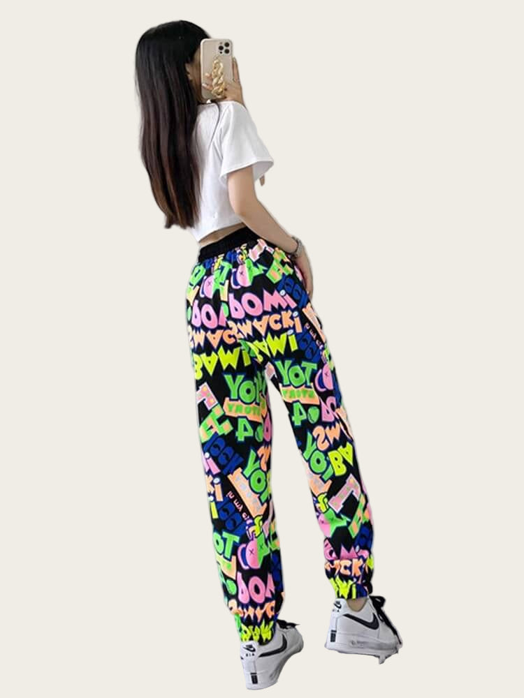 Person wearing colorful graphic pants with a white shirt, standing in front of a mirror.