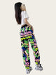 Person wearing colorful graphic pants with a white shirt, standing in front of a mirror.