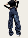 Person wearing blue jeans with a floral design, black crop top, and black gloves.