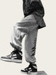 Person wearing light gray pants with black designs and black and white sneakers