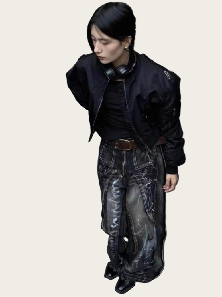 Person wearing a black jacket and dark pants against a yellow wall.