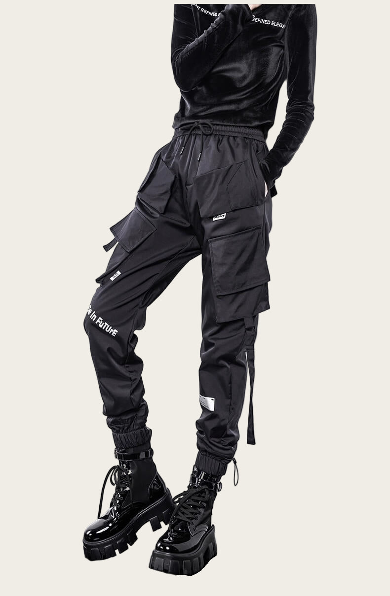 Person wearing black cargo pants with visible branding on a yellow background