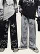 Two people wearing pants with butterfly and chain designs