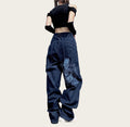 Person wearing blue jeans with a white design.