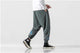 Person wearing green baggy pants and black high-top sneakers on a yellow background