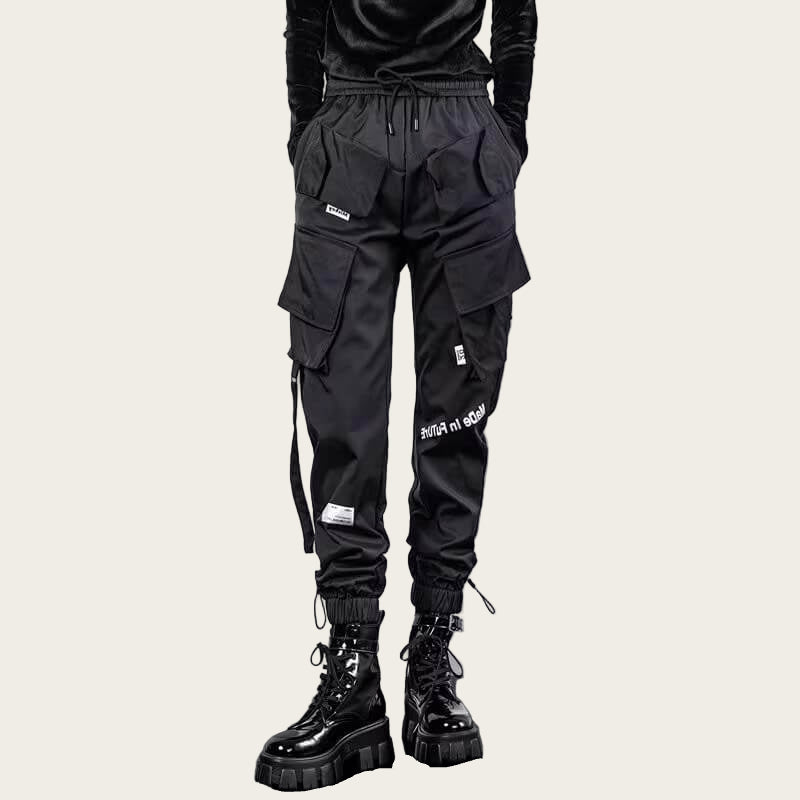Person wearing black cargo pants with multiple pockets and a yellow background