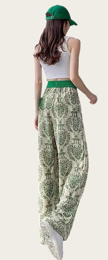 Person wearing a white top, green patterned pants, and a green cap.