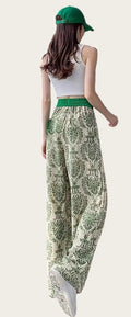 Person wearing a white top, green patterned pants, and a green cap.