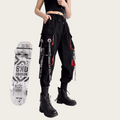 Person wearing black pants with red accents and a crop top, standing next to a skateboard with visible branding.