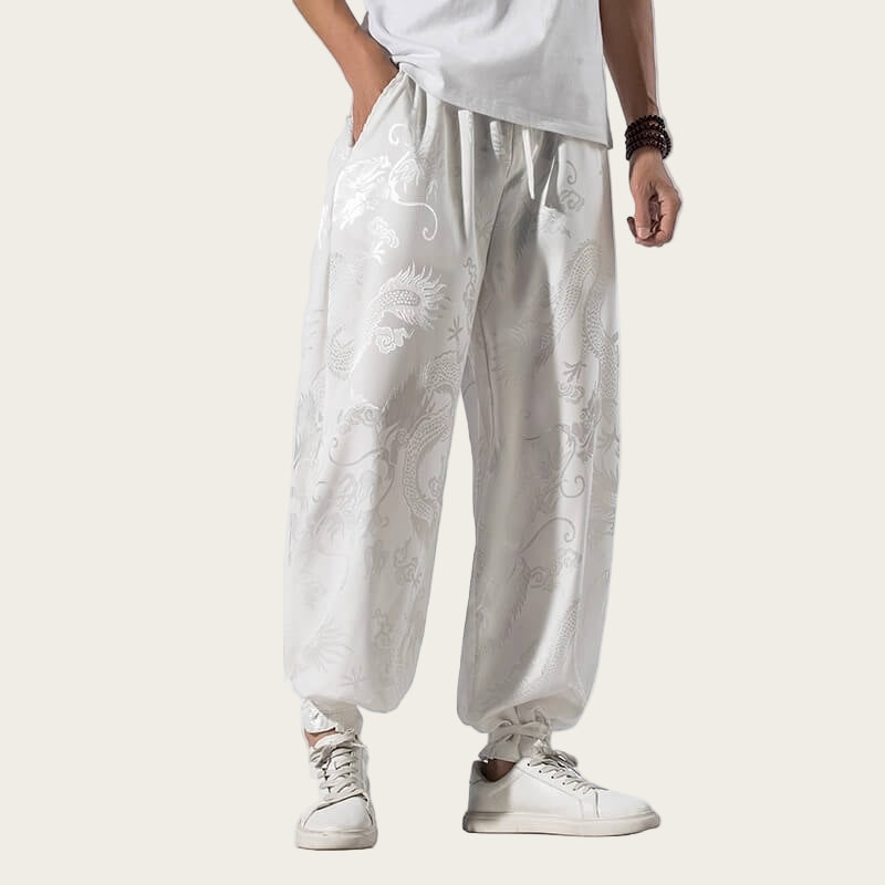 Person wearing white pants with floral patterns and white sneakers on a yellow background