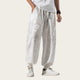 Person wearing white pants with floral patterns and white sneakers on a yellow background