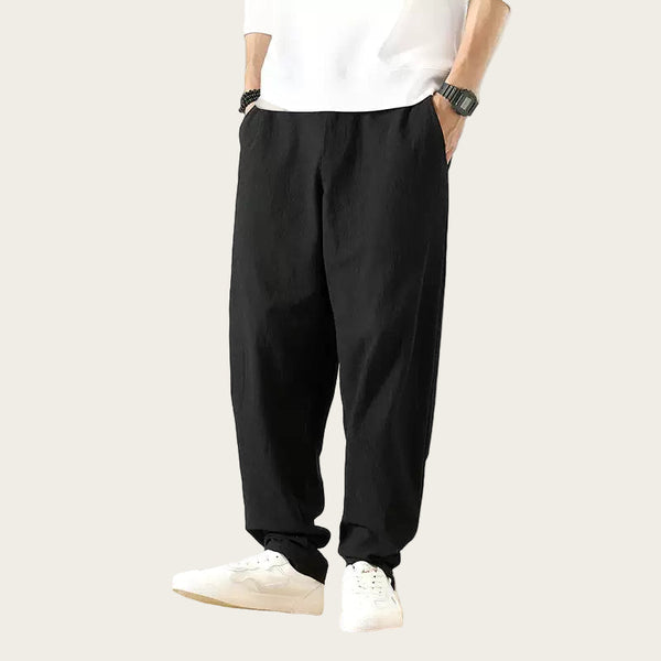 Person wearing black pants and white shoes in a yellow background