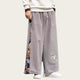 Person wearing gray wide-leg pants with colorful patterns