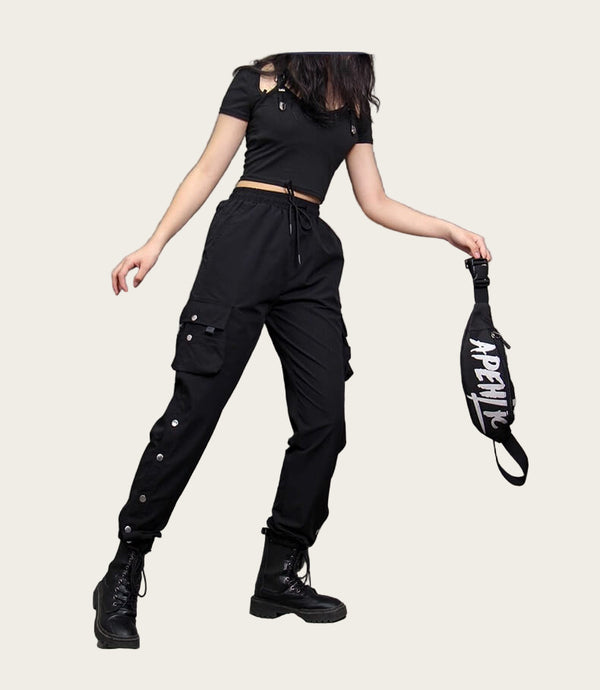 Person wearing a black outfit with cargo pants and holding a black bag