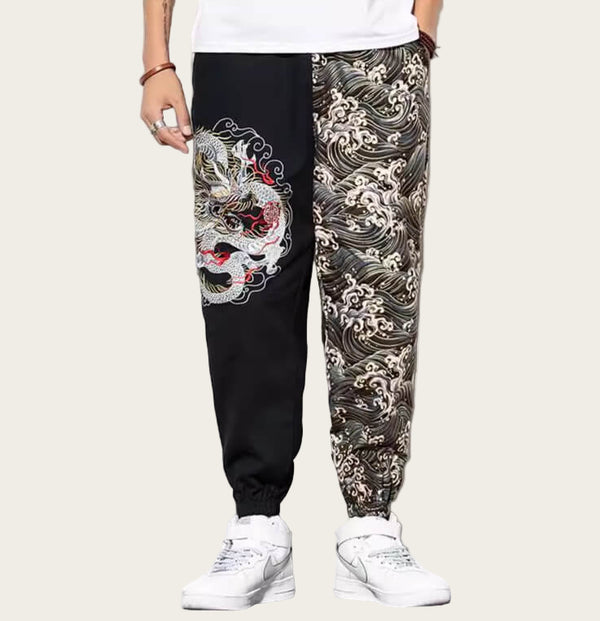 Black jogger pants with a dragon design on one leg, worn by a person