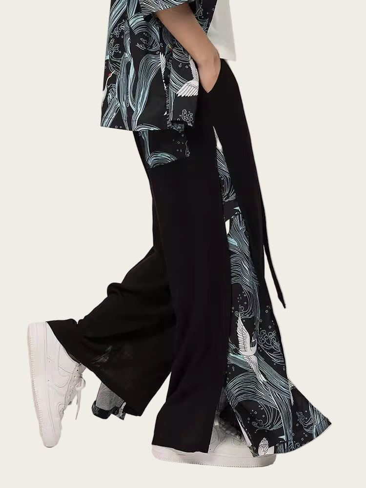 Person wearing a black and white patterned kimono-style garment with wide-leg pants on a plain background