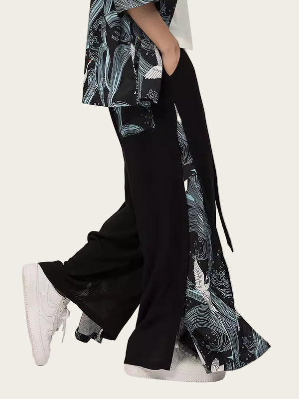 Person wearing a black and white patterned kimono-style garment with wide-leg pants on a plain background
