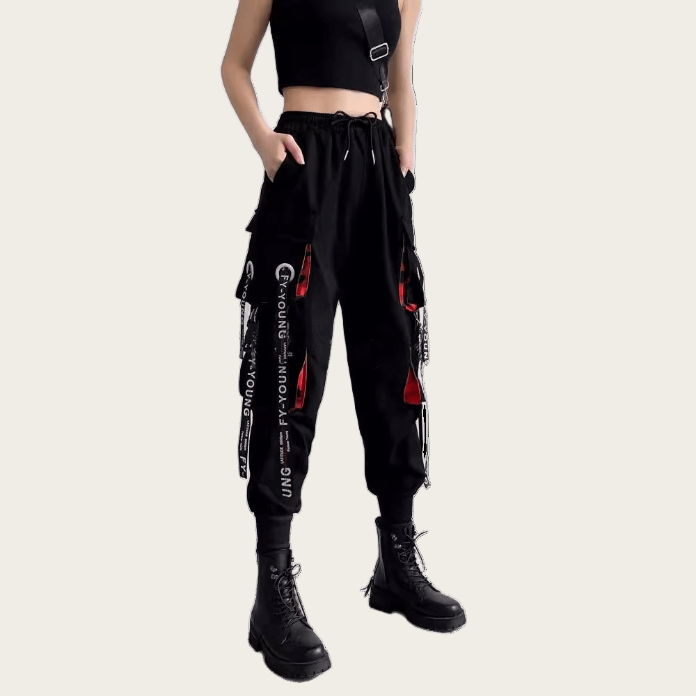 Person wearing black jogger pants with white text and red accents on a yellow background