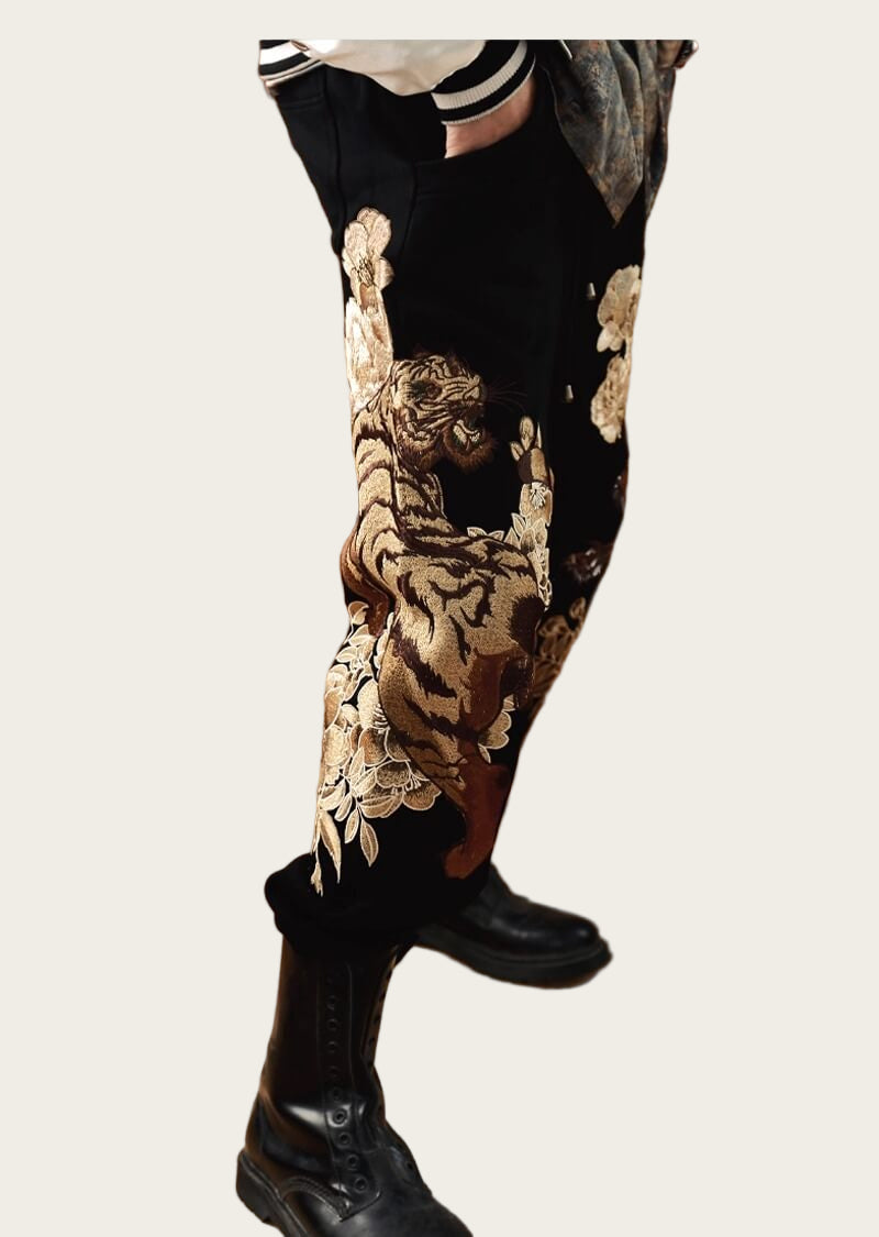 Person wearing black pants with gold floral patterns and black boots
