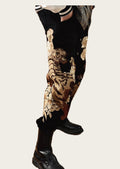Person wearing black pants with gold floral patterns and black boots