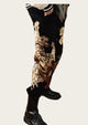 Person wearing black pants with gold floral patterns and black boots