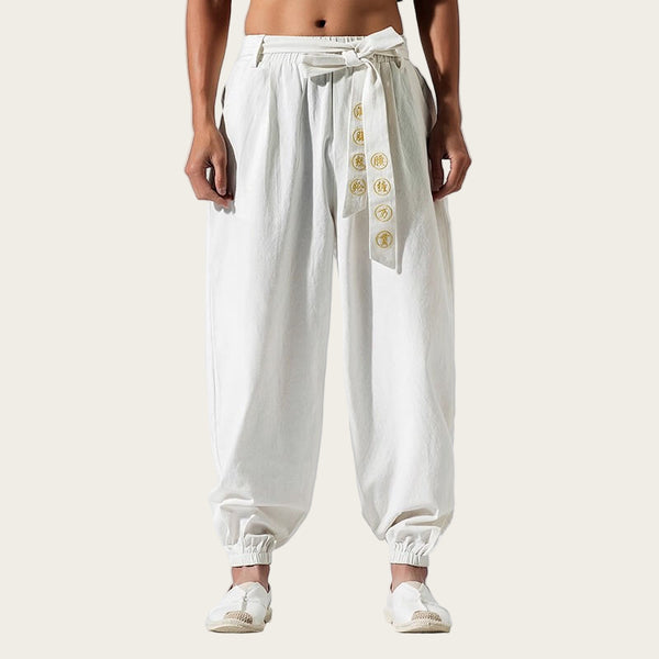 White pants with gold buttons worn by a person on a yellow background