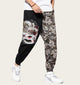 Person wearing black and white floral-patterned pants with a white top and white shoes on a yellow background