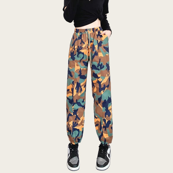 Camouflage pants worn by a person on a plain background