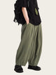 Person wearing olive green wide-leg pants with a black backpack