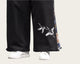Black pants with bird embroidery worn by a person, paired with white shoes