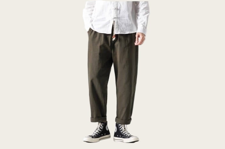 Person wearing a white shirt and green pants with black shoes