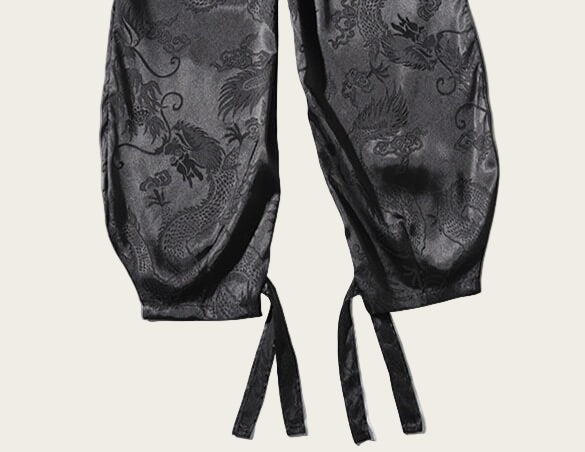 Black satin lingerie with intricate patterns on a white background