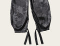 Black satin lingerie with intricate patterns on a white background