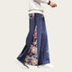 Person wearing navy pants with colorful patterns and a white sweater