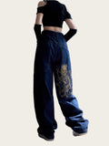 Person wearing a black crop top and blue jeans with a dragon design