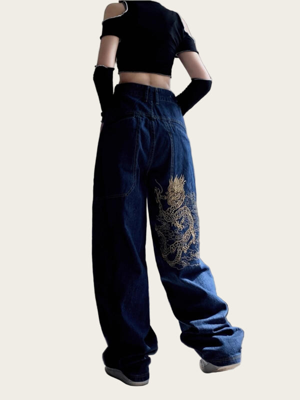 Person wearing a black crop top and blue jeans with a dragon design