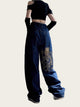 Person wearing a black crop top and blue jeans with a dragon design