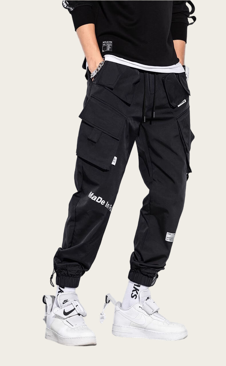 Person wearing black cargo pants with white sneakers on a yellow background