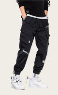 Person wearing black cargo pants with white sneakers on a yellow background