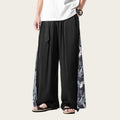 Person wearing black wide-leg pants with white patterns on a white background