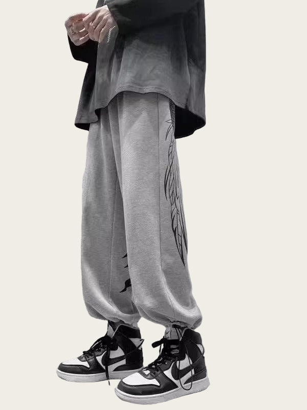 Person wearing gray sweatpants with a design, black jacket, and black and white sneakers 