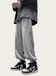 Person wearing gray sweatpants with a design, black jacket, and black and white sneakers 