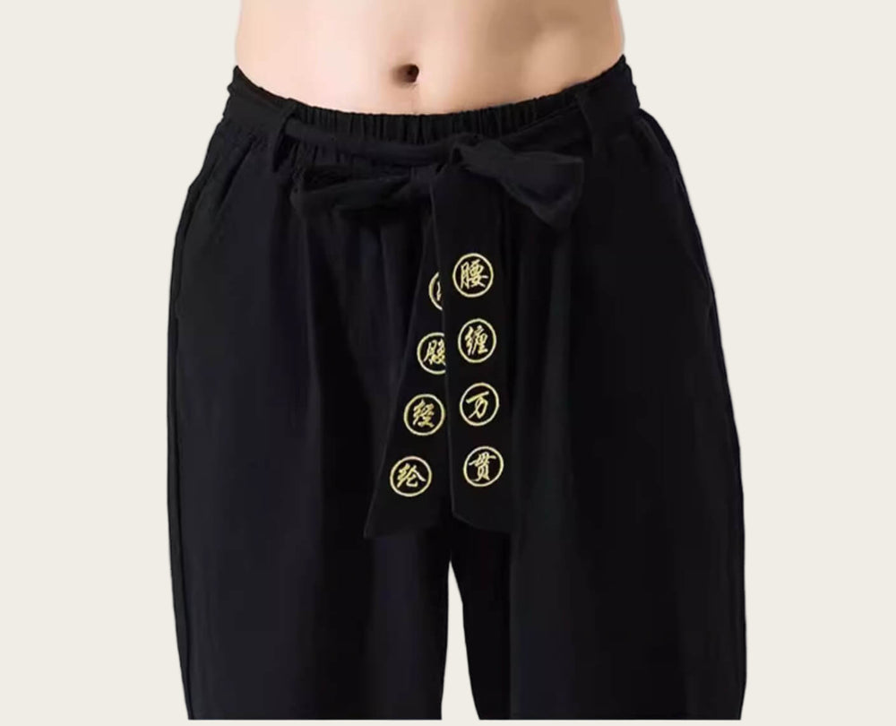 Black pants with gold embroidered symbols on a yellow background