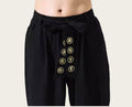 Black pants with gold embroidered symbols on a yellow background