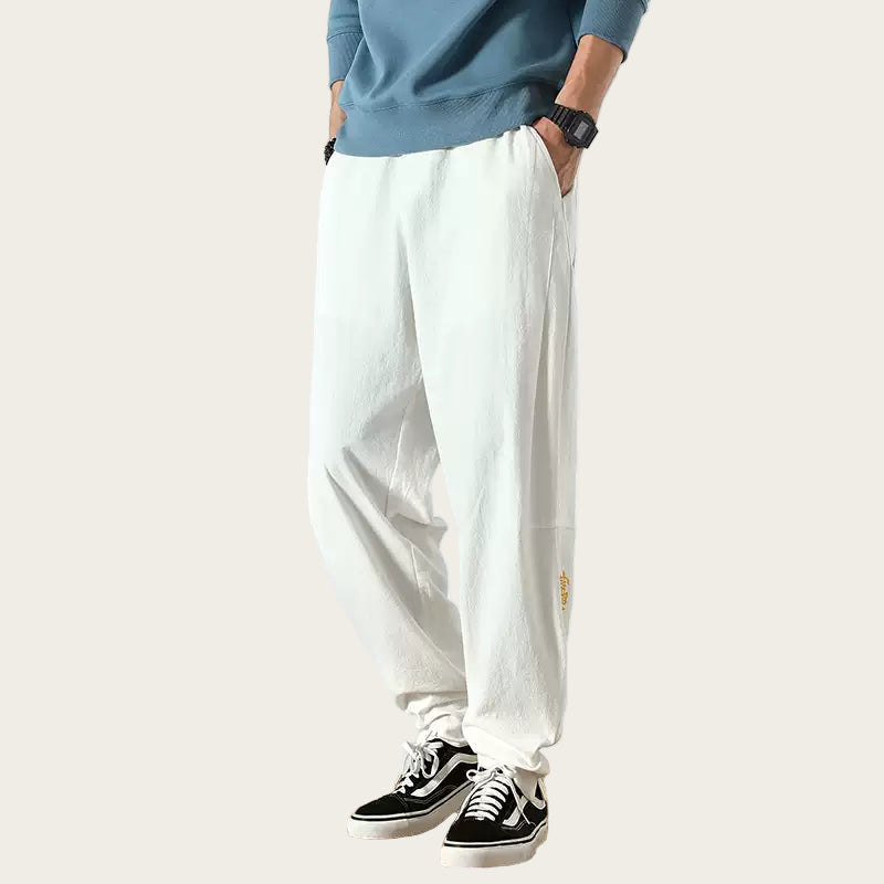 Person wearing white pants and black sneakers in a room.