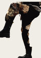 Black knee-high boots with floral embroidery on a decorative background