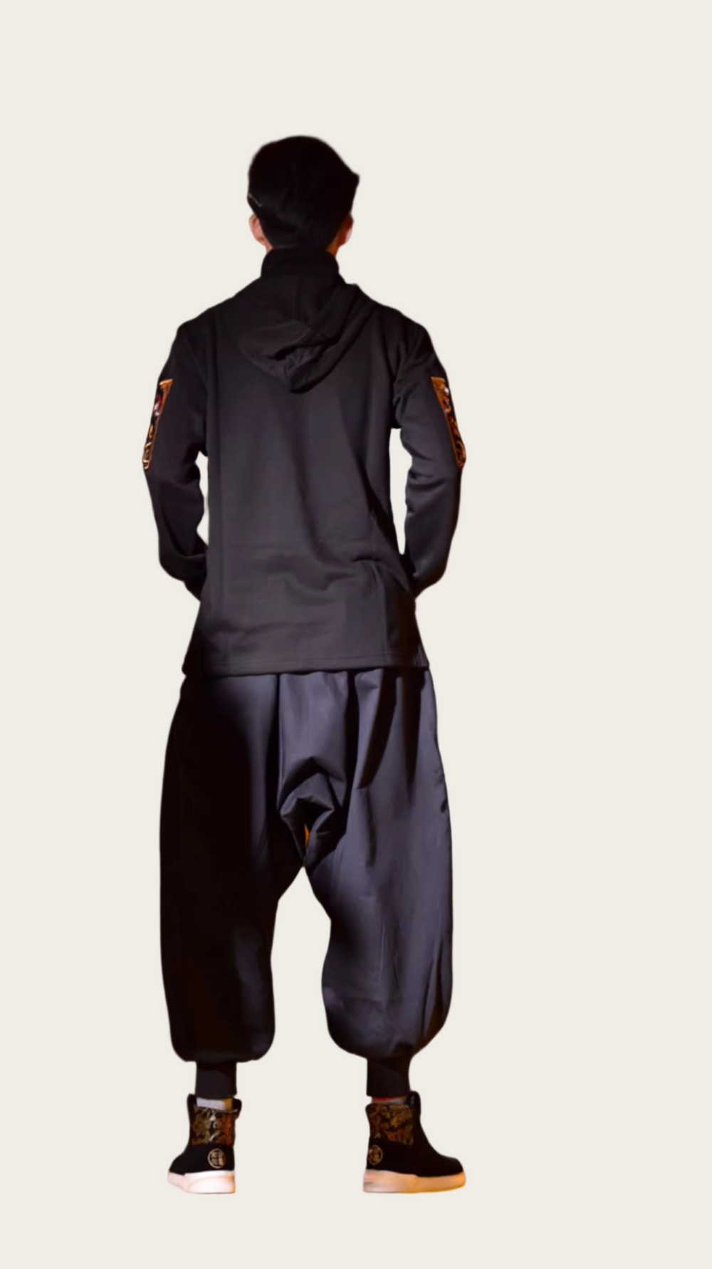 Person wearing a dark outfit with patches on a gradient background