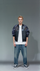 Man wearing a bomber jacket with floral pattern, white t-shirt, and blue jeans on a gray background